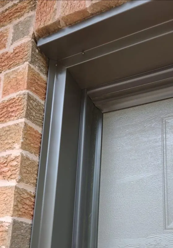 Dark aluminum capping around a garage door frame beside brickwork